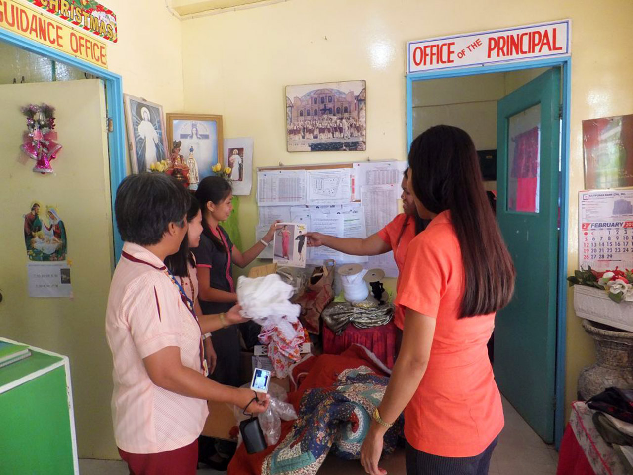 Teachers and principal opening box of donated sewing material